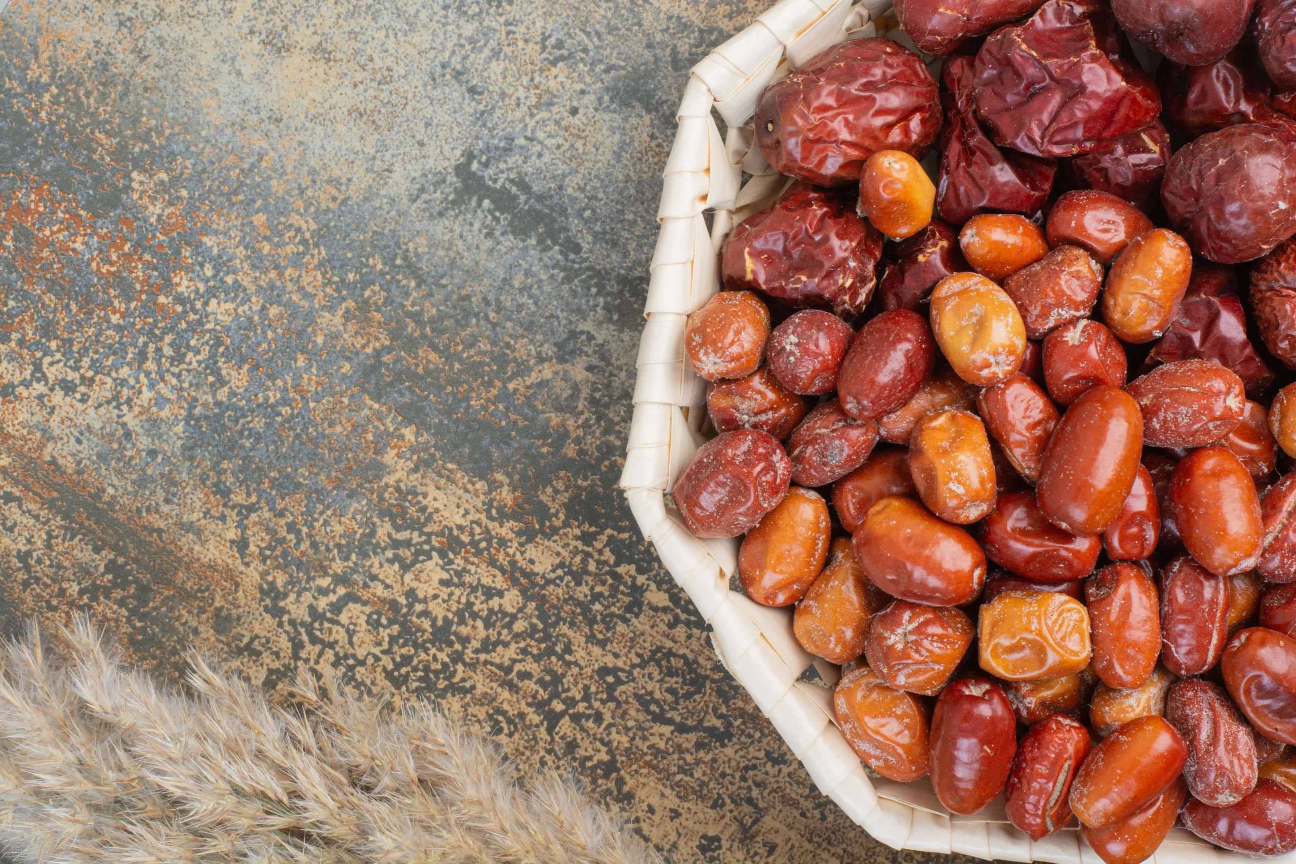 A bowl of dates on a wooden table in a natural setting."