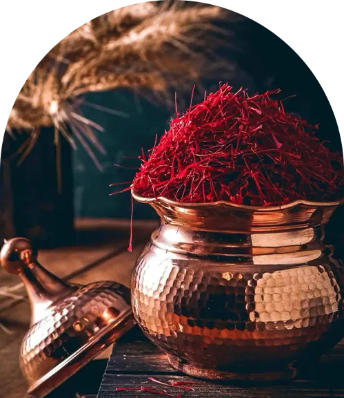 A copper container filled with a mound of vibrant Iranian saffron strands, set against a rustic background.